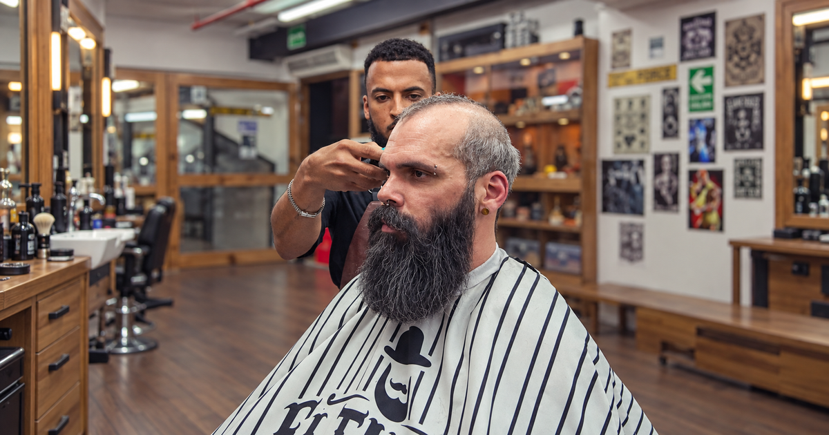 El Turco barber grooming a client's full beard in the barbershop